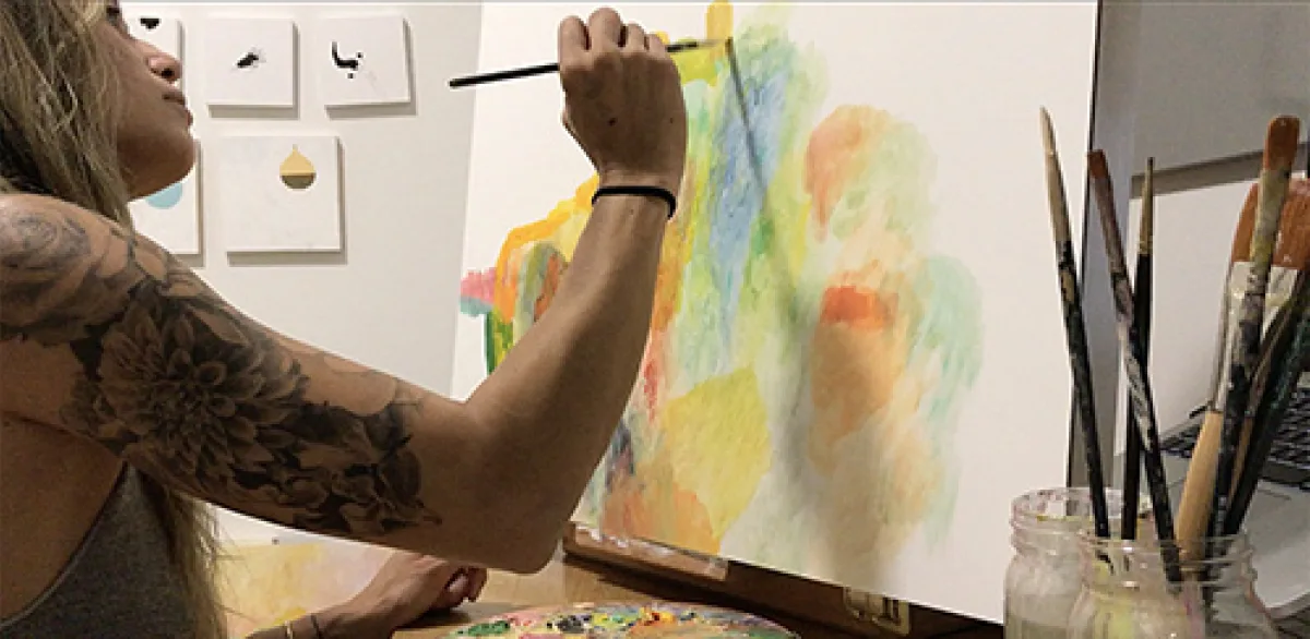 Betsy Lam paints a colorful abstract landscape painting with oils while sitting at her desk